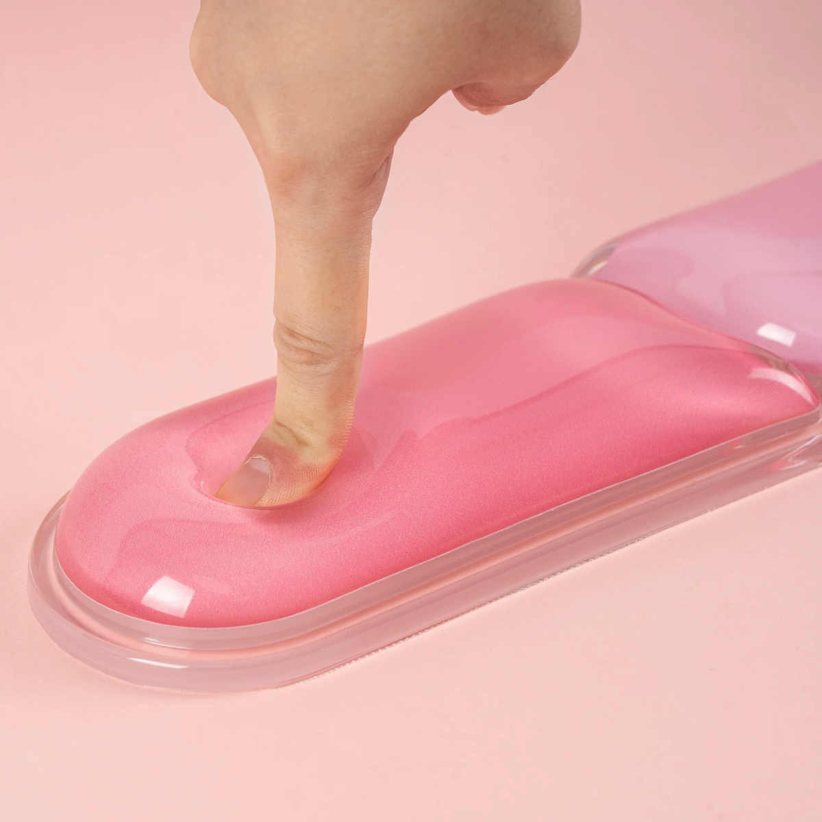 Finger pressing the pink EPOMAKER CloudGel keyboard wrist rest to show its soft cushion