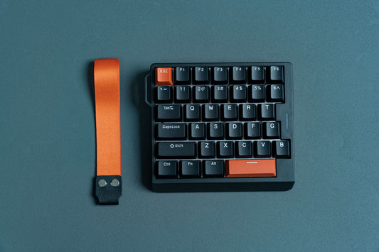 Black EPOMAKER HE30 one-handed Hall Effect gaming keyboard with orange accents and integrated carry strap